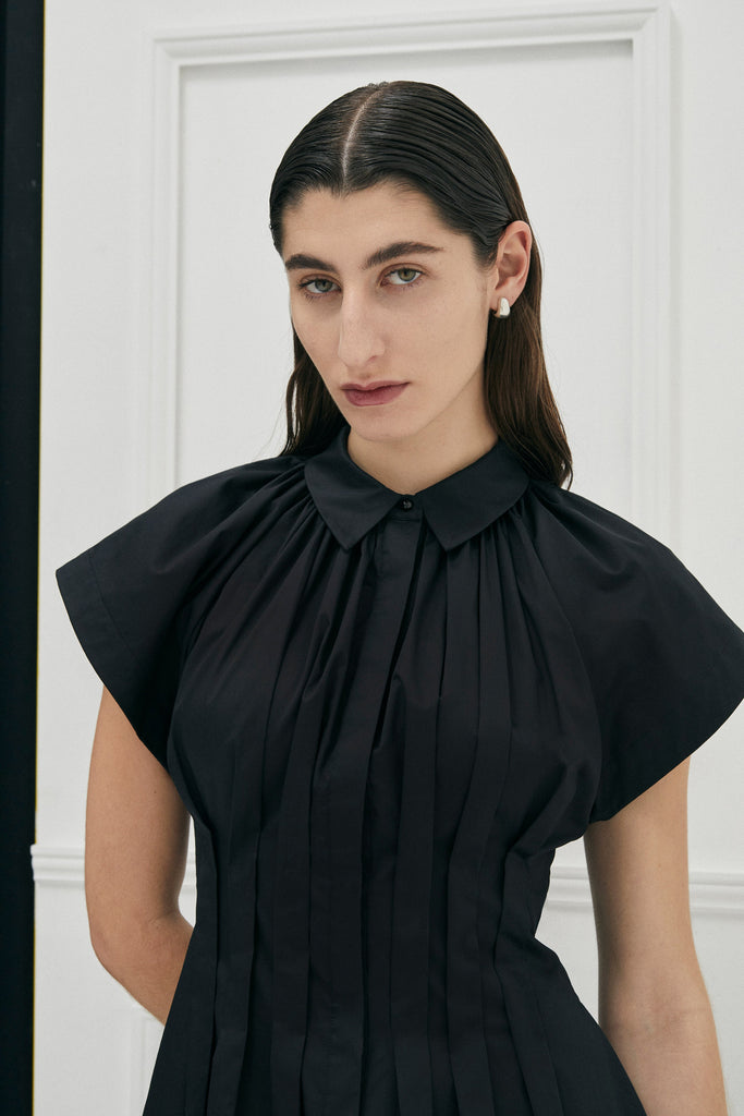 Unchartered shirt dress in Black Cotton by Australian Designer PALMA MARTÎN.  This long black dress style is uniquely tapered at the waist with pleats giving a flattering silhouette. 